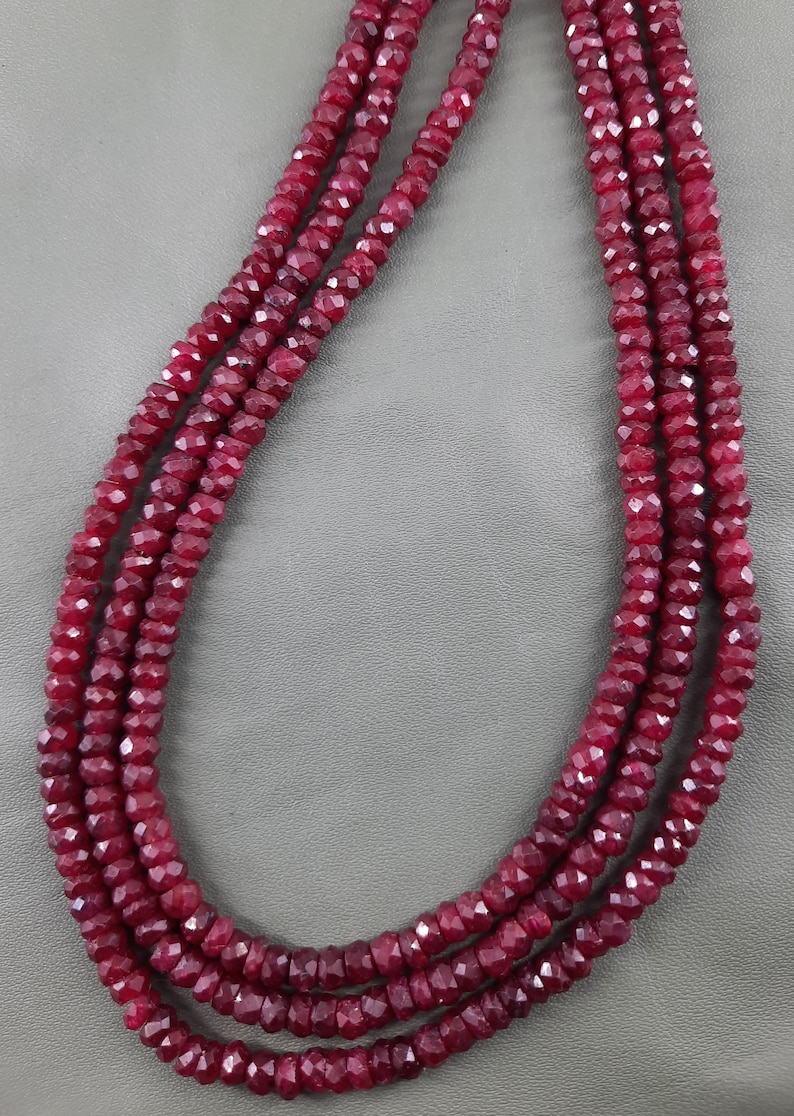 Puede incluir: Un collar de cuentas de rub&iacute; rojo oscuro, facetadas y enhebradas en tres filas.