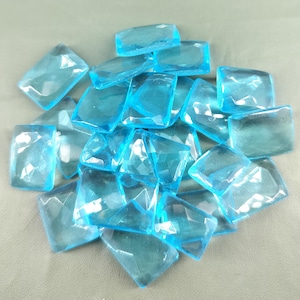 Puede incluir: Un montón de azulejos de vidrio facetado transparente azul claro. Los azulejos son rectangulares y tienen un aspecto ligeramente esmerilado.