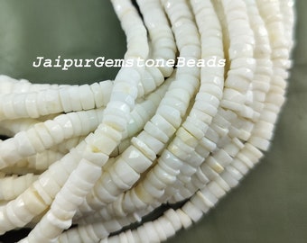 May include: A strand of white shell beads, each bead is a flat, irregular shape with a slightly iridescent finish. The beads are strung together to create a long necklace or bracelet.