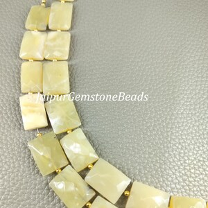 May include: A strand of light yellow gemstone beads with a faceted rectangular shape. The beads are strung on a gold wire and are arranged in a staggered pattern.