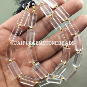 May include: A strand of clear quartz crystal beads with gold spacers. The beads are rectangular in shape and have a smooth, polished finish. The strand is approximately 18 inches long.