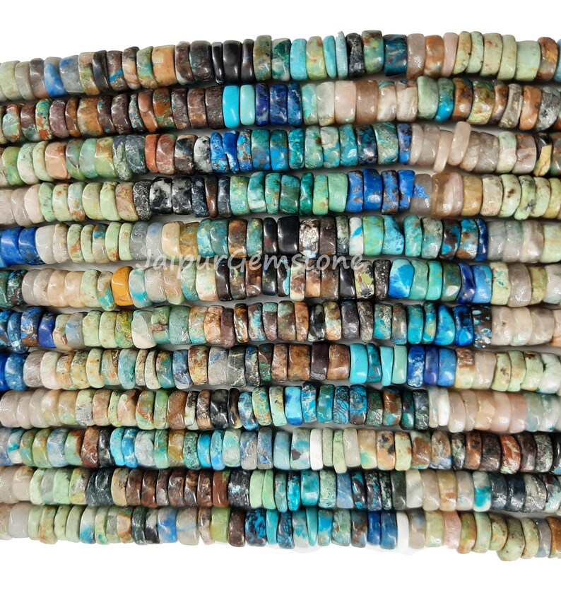 May include: A strand of mixed gemstone beads, featuring a variety of colors and patterns. The beads are small and round, with a mix of turquoise, blue, brown, and green hues. The beads are strung on a clear thread and are ready to be used for jewelry making.
