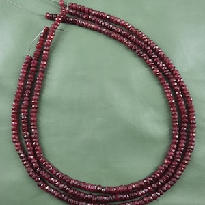 Puede incluir: Tres hebras de cuentas facetadas de color rojo rub&iacute; enhebradas en un alambre de plata.