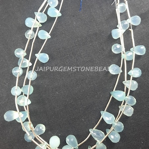 May include: A strand of light blue gemstone beads in a teardrop shape. The beads are strung on silver wire and are arranged in a cascading pattern. The beads are approximately 10mm in size.