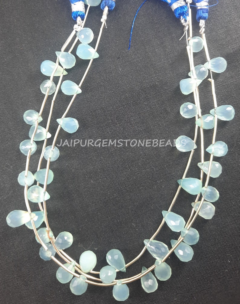 May include: A strand of light blue gemstone beads in a teardrop shape. The beads are strung on silver wire and are arranged in a cascading pattern. The beads are approximately 10mm in size.