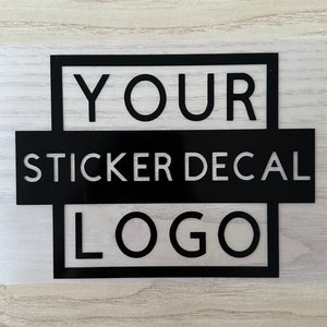 May include: Black and white sticker decal with the text "YOUR STICKER DECAL LOGO" in a square frame.