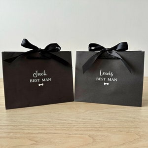 Pode incluir: Duas sacolas de presente pretas com la&ccedil;os de fita de cetim preto. As sacolas t&ecirc;m texto branco que diz "Jack Best Man" e "Lewis Best Man" com um pequeno &iacute;cone de gravata borboleta.