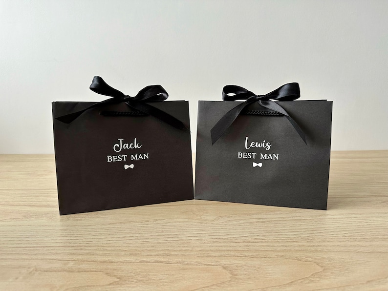 Pode incluir: Duas sacolas de presente pretas com la&ccedil;os de fita de cetim preto. As sacolas t&ecirc;m texto branco que diz "Jack Best Man" e "Lewis Best Man" com um pequeno &iacute;cone de gravata borboleta.