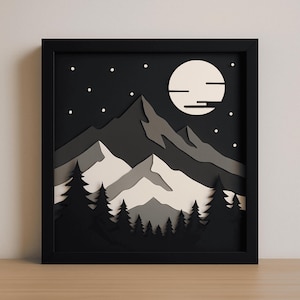 May include: A framed, layered paper art piece depicting a mountain scene at night. The artwork features a black frame, a dark night sky with stars, a full moon, and layered mountains in shades of gray and white, with a forest silhouette.