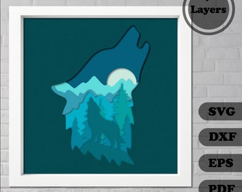 Op de afbeelding: Een gelaagd papierkunstig ontwerp van een wolf die huilt naar de maan, met een boslandschap in de silhouet van de wolf. Het ontwerp is in tinten blauw en groen, met een witte maan.