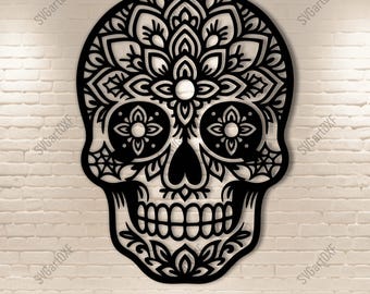 May include: Black, intricately designed skull with floral patterns, cut from a single piece. The skull features detailed eye sockets, a nose, and a full set of teeth. The design includes the text "SVG DXF PNG PDF" at the bottom. The skull is set against a white brick wall.