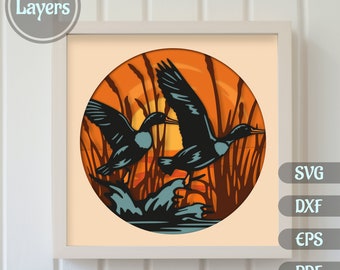 May include: A layered papercraft design featuring two ducks flying over a sunset scene with tall grass and water. The design is in a circular frame and has 10 layers.
