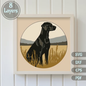 May include: A black dog sitting in a field of tall grass. The dog is looking to the right. The background is a field with hills in the distance. The image is in a circle shape.