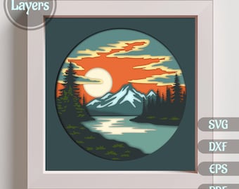 May include: A 12-layer paper cut design of a mountain lake scene with a full moon and sunset sky. The design is in a circular frame and is ready to be cut out.
