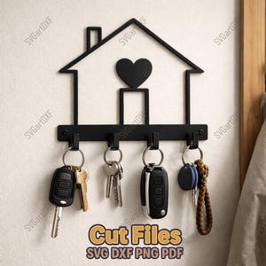 Puede incluir: Llavero de metal negro con forma de casa con un corazón. Tiene cuatro ganchos que sostienen llaves y llaveros. El texto "Cut Files SVG DXF PNG PDF" está en amarillo y marrón en la parte inferior.