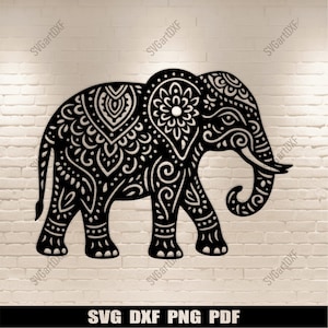 Może przedstawiać: Czarna dekoracyjna sylwetka słonia ze skomplikowanymi wzorami kwiatowymi i paisley. Słoń idzie, z podwiniętą trąbą. Obraz zawiera tekst "SVG DXF PNG PDF". Słoń jest umieszczony na tle białej ceglanej ściany.