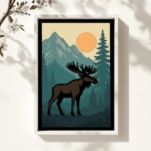 May include: A framed art print featuring a moose in a forest scene. The moose is brown with large antlers, set against a backdrop of teal trees, mountains, and a yellow sun. The artwork is framed in a white border.