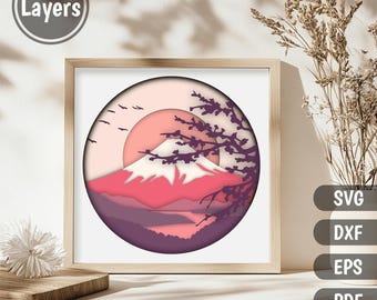 May include: A digital papercraft design featuring a layered, pink and purple mountain scene with a cherry blossom tree and a sun in the background. The design is in a circle and has 11 layers.