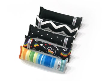 May include: Five catnip toys with different patterns. The toys are black with white polka dots, black with white zigzags, black with a rainbow and hearts, black with a rainbow and arrow, and blue and yellow stripes.