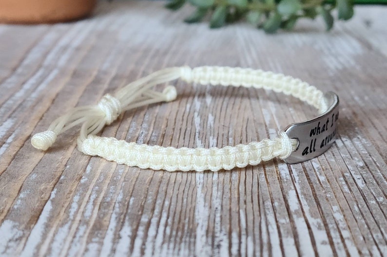 Puede incluir: Una pulsera trenzada blanca con un dije plateado que dice "what I've been through makes me stronger".