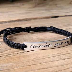 May include: Black braided bracelet with a silver metal tag that reads "remember your why".