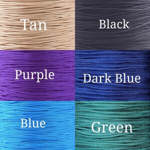 Op de afbeelding: Een verzameling gekleurde koorden in beige, zwart, paars, donkerblauw, blauw en groen. Elke kleur is gelabeld met witte tekst. De koorden zijn dicht op elkaar gepakt, waardoor een textuur ontstaat.