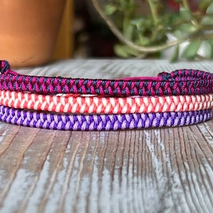 May include: Three braided bracelets in purple, red and white, and black and pink.