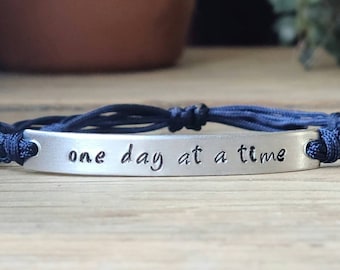 Un día a la vez / Pulsera estampada a mano / Pulsera de barra de aluminio ajustable / Pulsera de cordón de nailon / Banda de color a elegir