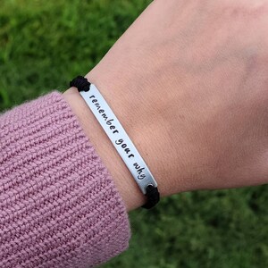 May include: A black elastic bracelet with a silver metal bar that reads "remember your why".
