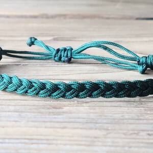 May include: A dark green braided cord bracelet with adjustable closure. The bracelet is made of a soft, durable cord and is perfect for everyday wear.