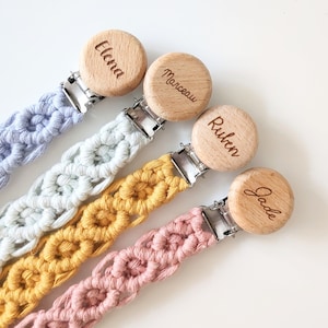 Può includere: Quattro morsi per bambini in legno con nomi personalizzati, Elena, Marceau, Ruben e Jade, attaccati a clip per ciucci all'uncinetto in blu, bianco, giallo e rosa.