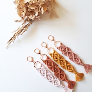 Peut inclure: Ensemble de cinq porte-clés en macramé avec des anneaux de clés dorés. Les porte-clés sont faits de différentes couleurs, dont le rose, l'orange et le jaune.