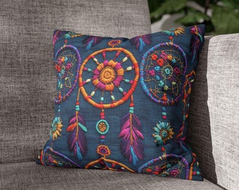 May include: A decorative throw pillow with a dark blue background and embroidered dreamcatcher design. The dreamcatchers feature colorful details in orange, pink, purple, and teal. The pillow is placed on a gray sofa.