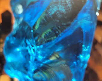 May include: A close-up of a blue glass filled with a clear liquid. The liquid is swirling and creating a blue and white pattern.