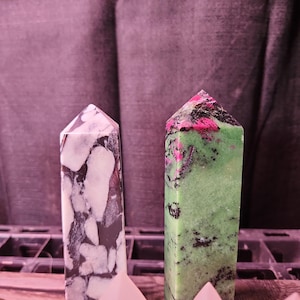 Puede incluir: Dos puntas de cristal pulidas, una con un patrón de mármol blanco y negro y la otra con un patrón de mármol verde, negro y rosa.