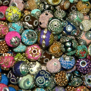 May include: A collection of colorful and patterned beads, featuring a variety of textures and designs. The beads are made from different materials, including glass, metal, and plastic. They are perfect for jewelry making, crafting, and home decor.