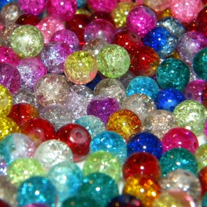 May include: A collection of colorful, sparkly glass beads. The beads are round and have a textured surface. They are a variety of colors, including red, blue, green, yellow, pink, and purple.
