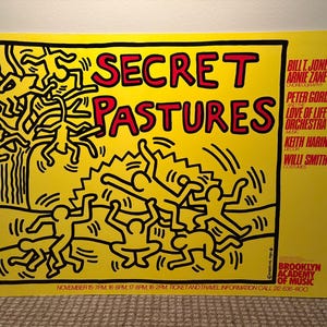 Puede incluir: Un cartel amarillo con texto e ilustraciones en negro y rojo. Las palabras "SECRET PASTURES" est&aacute;n en letras rojas grandes. El cartel presenta figuras de palo y los nombres de los artistas. El logotipo de la Brooklyn Academy of Music est&aacute; en la esquina inferior derecha.