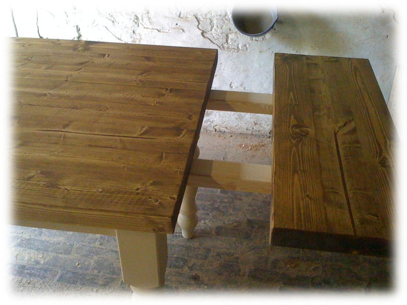 May include: A wooden table with a brown top and white legs. The table has a leaf that can be extended to make it longer.