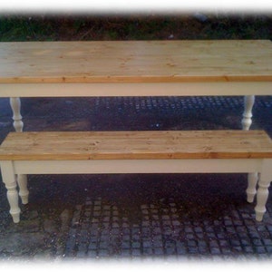 May include: A white painted wooden table and bench set with a natural wood top. The table has turned legs and the bench has turned legs on the front.