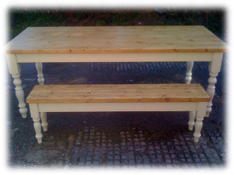 May include: A white painted wooden table and bench set with a natural wood top. The table has turned legs and the bench has turned legs on the front.