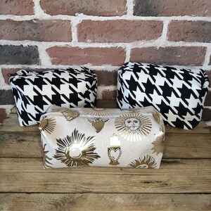 May include: Three cosmetic bags. Two are black and white houndstooth fabric. One is beige with gold metallic sun and heart designs.
