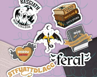 Op de afbeelding: Een verzameling stickers met fantasiethema's met draken, boeken en tekst. Stickers zijn onder meer "Basgiath War College", een draak met een maan, en gestapelde boeken met de titels "Forth Wing", "Iron Flame" en "Onyx Storm".