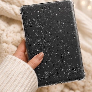 May include: A clear protective case for an electronic device. The case has a black background with a sparkling white star pattern. The case is held in a hand, showcasing the design.