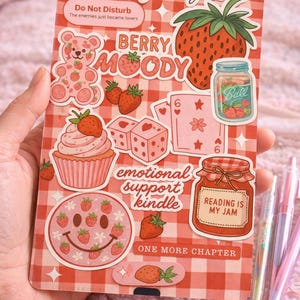 Può includere: Un foglio di adesivi decorativo con un motivo a quadri rossi e bianchi. Presenta illustrazioni di fragole e orsi, e testi come "Berry Moody", "Emotional Support Kindle" e "Reading is my Jam".