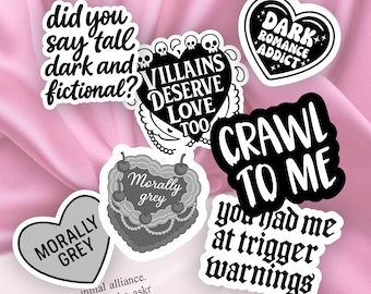 Puede incluir: Una colección de pegatinas blancas con texto y diseños en negro. Las pegatinas presentan frases como "Did you say tall, dark, and fictional?" y "Villains deserve love too". Otras pegatinas dicen "Morally grey" y "Crawl to me".