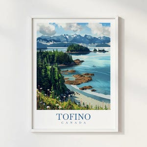 May include: A framed art print depicting a coastal scene with a beach, sea, and mountains. The artwork uses a painterly style with blues, greens, and whites. The text "TOFINO CANADA" is printed at the bottom of the print.