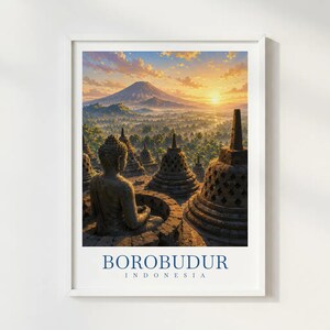 Op de afbeelding: Een ingelijste kunstdruk met een stenen Boeddhabeeld dat uitkijkt over het Borobudur-tempelcomplex in Indonesië bij zonsopgang, met een grote berg op de achtergrond. De tekst BOROBUDUR INDONESIA staat in blauw onderaan de witte rand gedrukt.