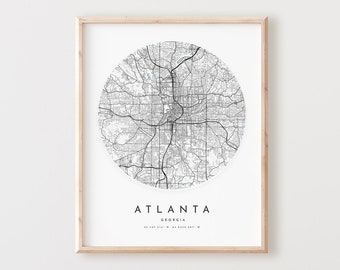 May include: Black and white print of a map of Atlanta, Georgia. The map is in a circle and shows the city's streets and roads. The text "Atlanta, Georgia" and the coordinates "33.4457° N, 84.2357° W" are printed below the map.
