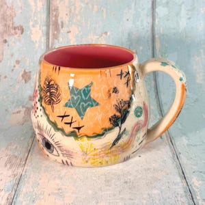 Tazza in ceramica arancione con collage, realizzata a mano.
